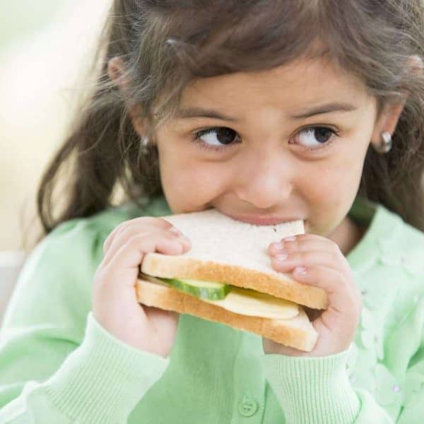 Little girl eating sandwich at home