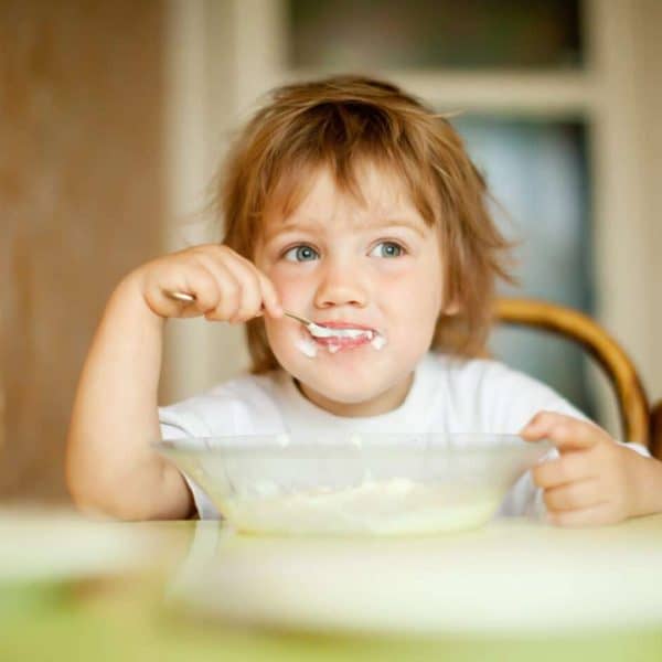 child eats with spoon in home